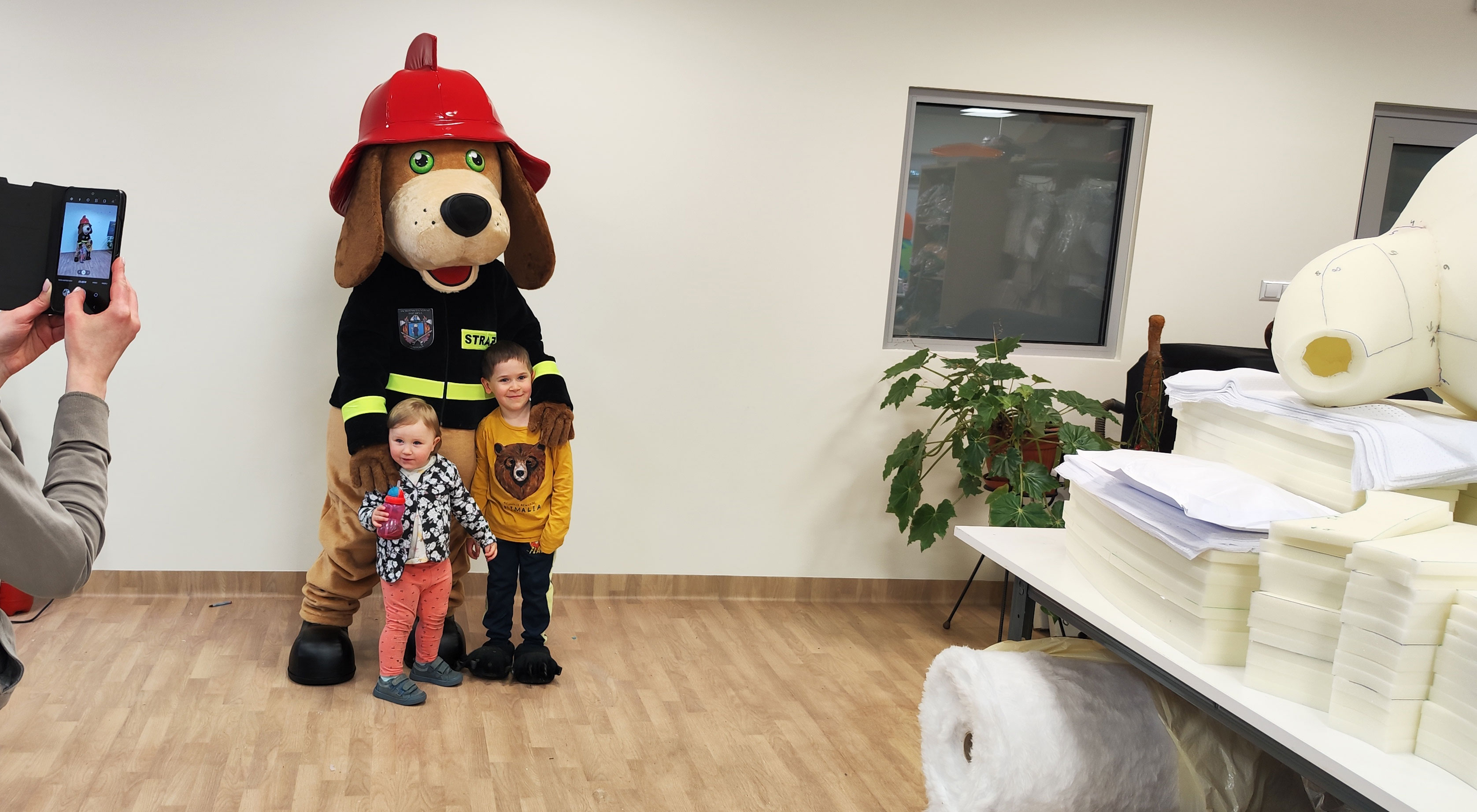 Na fotografii widnieje kostium reklamowy stylizowany na postać psa pozujący do zdjęcia w siedzibie firmy Elabika